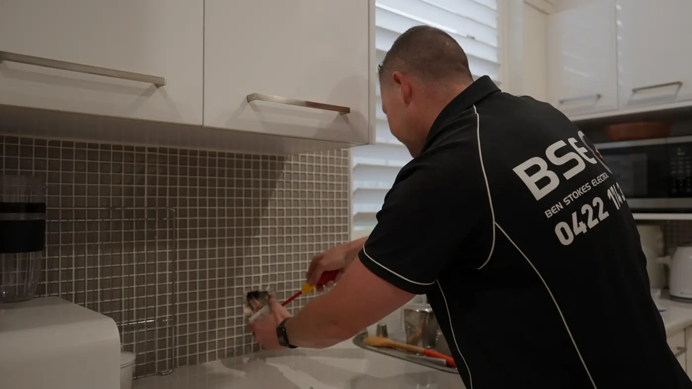 Ben fitting a power point into a tiled kitchen splashback